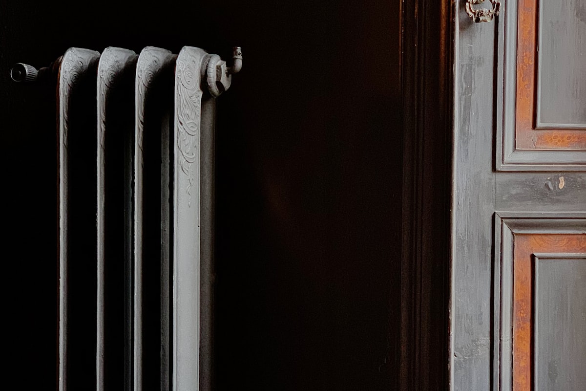Klassisk gjutjärnsradiator mot mörk vägg